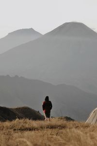 Rear view of woman standing on mountain against sky