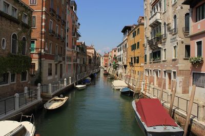 Canal amidst buildings in city against sky