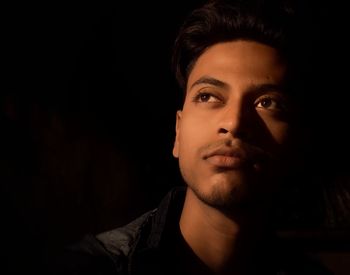 Portrait of young man against black background