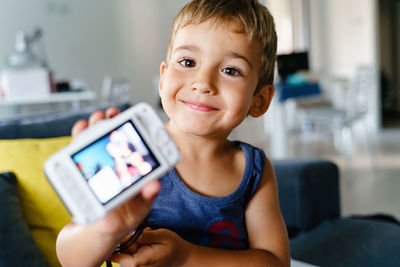 Portrait of boy holding mobile phone at home