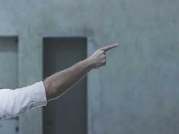 Cropped image of man pointing against wall