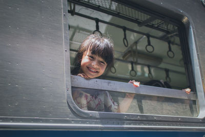 Portrait of smiling girl looking through train window