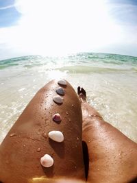 Midsection of woman at beach against sky