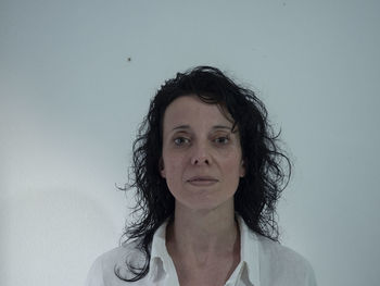 Portrait of young woman standing against wall