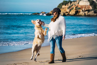 Woman feeding dog at sea shore