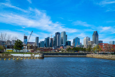 River by cityscape against blue sky