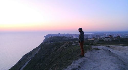 Man looking at sea against sky during sunset