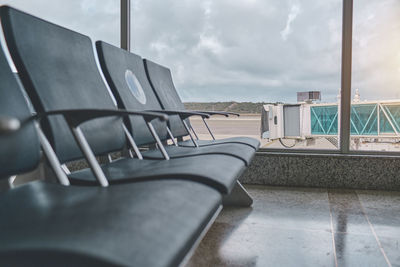 Empty chairs in the departure hall at airport, blurred plane on a background.