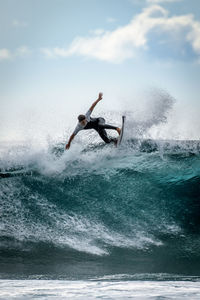 Surfer with wetsuit enjoying big waves in tenerife. sporty boy riding his surf board on the wave.