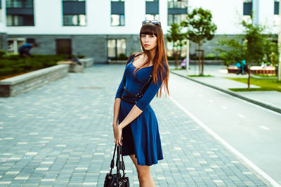 Full length portrait of young woman standing in city