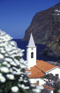 High angle view of clock tower and church by sea