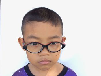 Close-up portrait of boy standing against white background