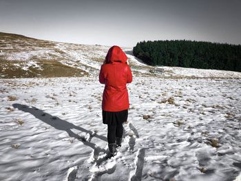 Woman with red hoodie walking on the snow in the mountains