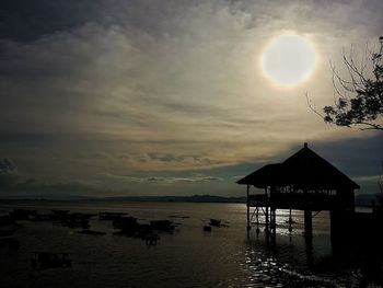 Silhouette built structure by sea against sky during sunset