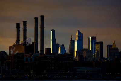 Modern buildings in city against sky during sunset