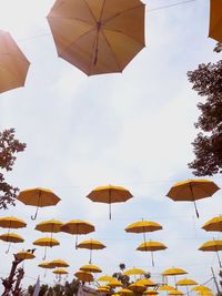 Low angle view of umbrellas hanging against sky