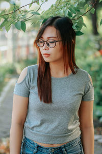 Portrait of young woman standing against plants