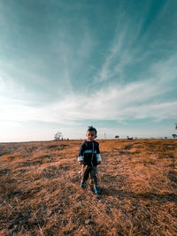 Full length of young man standing on field against sky