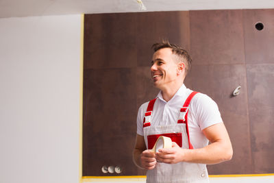 Young man smiling while standing against glass wall