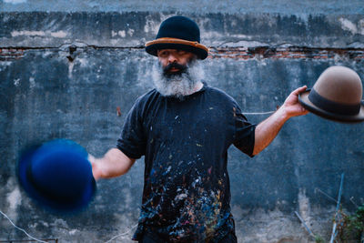 Portrait of man juggling with hats