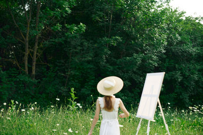 Full length of woman standing by tree on field