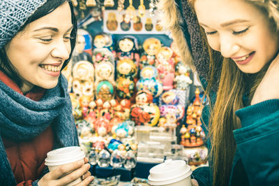 Close-up of smiling woman drinking coffee at store