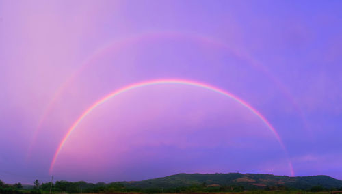 Scenic view of rainbow over mountain against sky