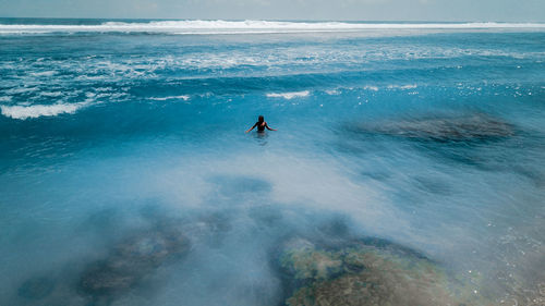 Aerial view of woman standing at sea