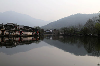 Reflection of houses in lake against clear sky
