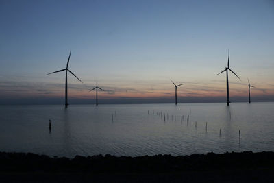 Wind turbines located in the ijsselmeer in the netherlands photographed after sunset.