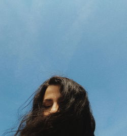 Low angle portrait of woman against blue sky