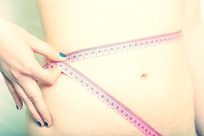 Midsection of woman measuring her waist