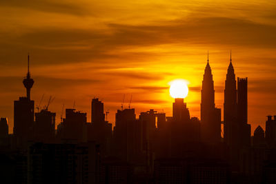 Silhouette of buildings against cloudy sky during sunset