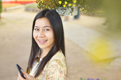 Portrait of smiling young woman using mobile phone outdoors