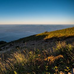 Scenic view of landscape and sea against clear blue sky