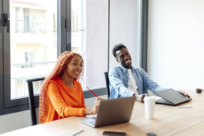 Happy business colleagues sitting at desk in office meeting