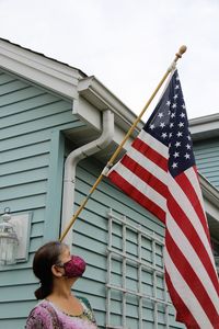 Low angle view of woman against building admiring  united states flag