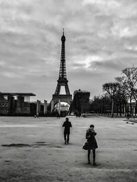 People on tower in city against cloudy sky