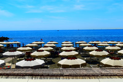 Deck chairs and parasols on beach against sky