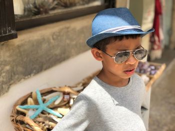 Portrait of boy wearing sunglasses and hat standing outdoors