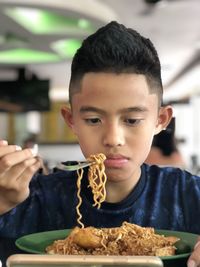 Close-up of boy eating food while sitting in restaurant