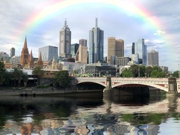 Bridge over river by buildings against sky in city
