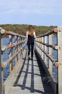 Rear view of woman on pier over lake