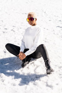 A young african american woman wearing sunglasses having fun in the snow on a winter day