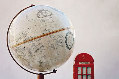 Close-up of globe by telephone booth against wall