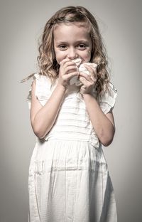 Portrait of a girl holding face against white background