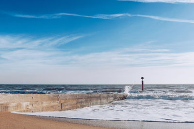 Rear view of man standing on beach against sky