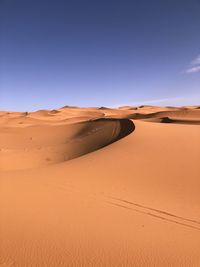 Sand dunes in sahara desert against clear blue sky