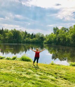 Rear view of person standing by lake against sky