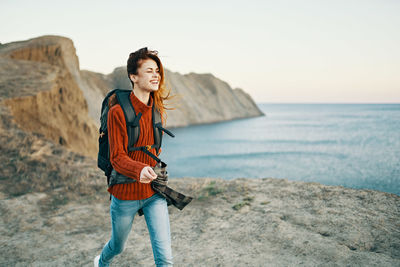 Full length of smiling young woman standing on beach